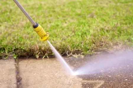 Cleaning a concrete sidewalk with a pressure washer